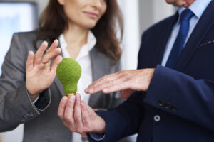 Representação de um consumo consciente de energia elétrica, demostrando por um homem segurando uma lampada verde feita de grama.