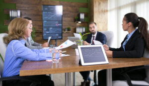 Empreendedores trabalhando em uma sala de conferência moderno. Mesa de madeira com gráficos em cima, eles analisam o impacto da reforma do setor elétrico para empresas.