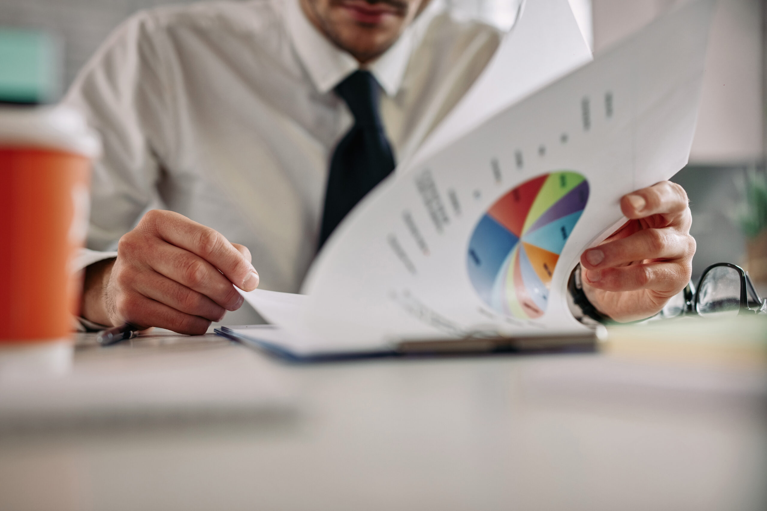 Close nas mãos de um homem dos planos analisando as estatísticas do preço da energia no mercado livre.